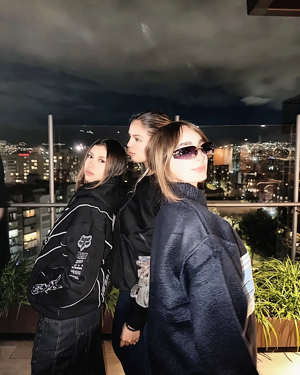 Tres personas en una terraza de noche con buzos Supreme Factory Team y tejido Supreme